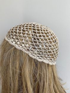 a woman's head wearing a white netted hat with buttons on the side