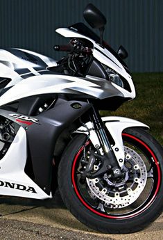 a white and black motorcycle parked in front of a building with red rims on it