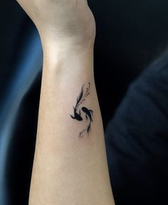 a woman's arm with a small black bird tattoo on it