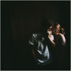 a man and woman standing next to each other in front of a dark room with the light on