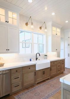 a large kitchen with white cabinets and wood flooring, along with a rug on the floor