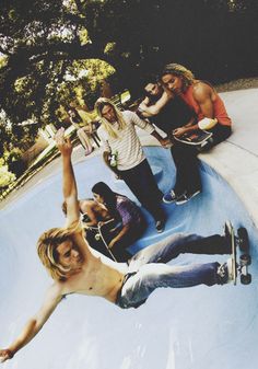 a group of young men riding skateboards on top of a blue ramp in a park