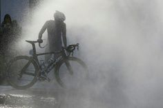 a man standing next to his bike in the water spraying from it's spewer