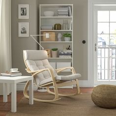 a living room with a rocking chair and bookshelf next to a table in front of a door