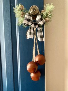 a blue door with two bells hanging from it's side and pine cones on the front