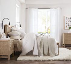 a bedroom with white walls and wooden floors has a bed, nightstands, and window