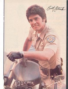 a police officer on a motorcycle with his hand on the handlebars and looking at the camera