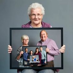 an elderly couple holding up a framed photo