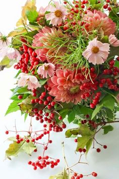 an arrangement of flowers and berries on a white background