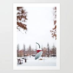 a photograph of a snow covered park with trees in the background and a red, white and green umbrella