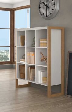 a clock mounted to the side of a white book shelf next to a large window