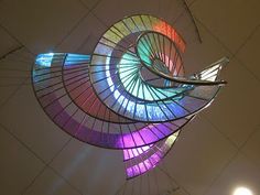 a large colorful sculpture hanging from the ceiling in a building with lights on it's sides