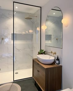 a white sink sitting under a bathroom mirror next to a walk in shower and toilet