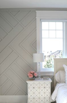 a white bed sitting next to a window in a bedroom