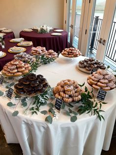 a table topped with lots of donuts and pastries on top of white tables cloths