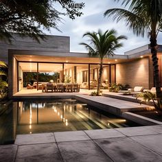 an outdoor swimming pool with lounge chairs and palm trees in the background at night time