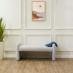 a white bench sitting next to a potted plant on top of a hard wood floor