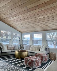 a living room filled with lots of furniture under a wooden ceiling mounted high up to the ceiling