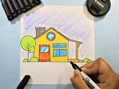 someone is drawing a house with colored pencils