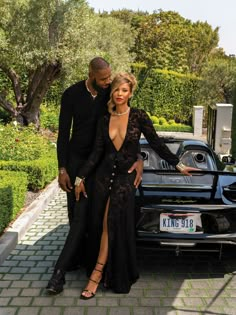 a man and woman standing next to a car