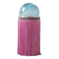 a pink and blue object with fringes on the bottom, sitting in front of a white background