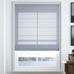 a white window with blue blinds in a room next to a table and pictures on the wall