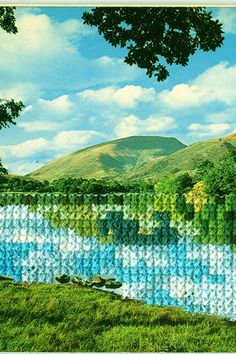 a painting of a river in the middle of a green field with mountains in the background