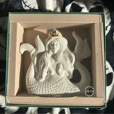 a white ceramic mermaid ornament in a box