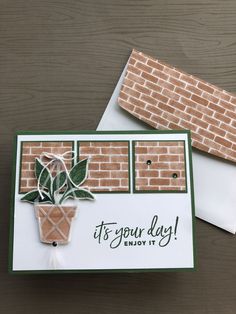 a close up of a card with a brick wall in the background and a potted plant on it