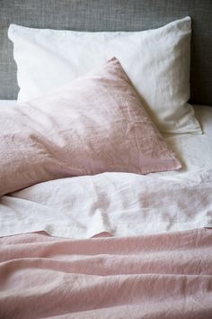 an unmade bed with pink sheets and pillows