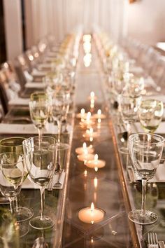 a long table is set with wine glasses and candles