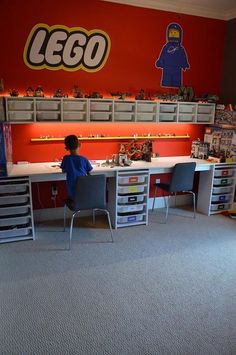 a young boy sitting at a desk in front of a lego wall