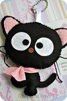 a black cat keychain with a pink bow around it's neck and eyes