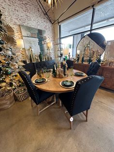 a dining room table with blue chairs and plates on it in front of a christmas tree