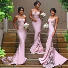 three bridesmaids in pink dresses standing on steps with bouquets and greenery