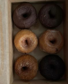 six donuts in a cardboard box on a table