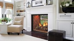 a living room filled with furniture and a fire place in front of a window on top of a hard wood floor