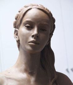 a statue of a woman with braids on her hair is shown in front of a white wall