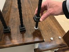 a person is holding two pieces of metal on top of a wooden table