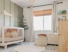 a baby's room with a crib, chair and ottoman