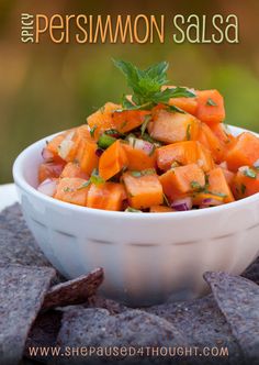 a white bowl filled with chopped up carrots on top of a wooden table next to crackers