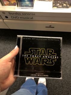 someone is holding up a star wars cd case in front of some movies on the shelf