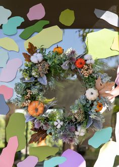 a wreath with flowers and leaves hanging on the side of a building in front of a mirror