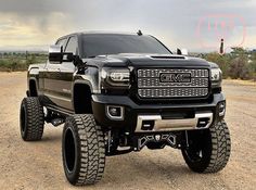 a large black truck parked on top of a dirt field