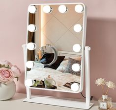 a white vanity mirror sitting on top of a table next to a vase with flowers