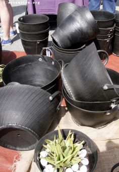 several black buckets with plants in them on the ground