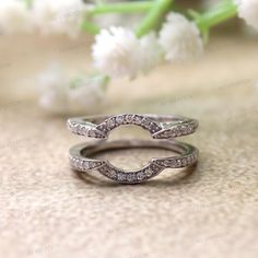 two white gold wedding bands with diamonds on top and bottom, sitting next to each other