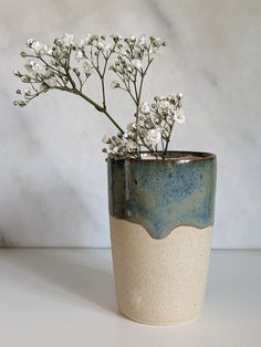 a white and blue vase filled with flowers on top of a marble countertop next to a wall