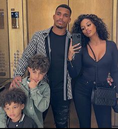 a man, woman and two children taking a selfie in front of a mirror