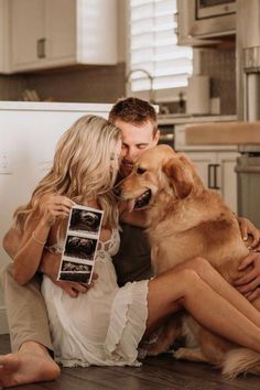 a man and woman sitting on the floor with a dog in front of their face